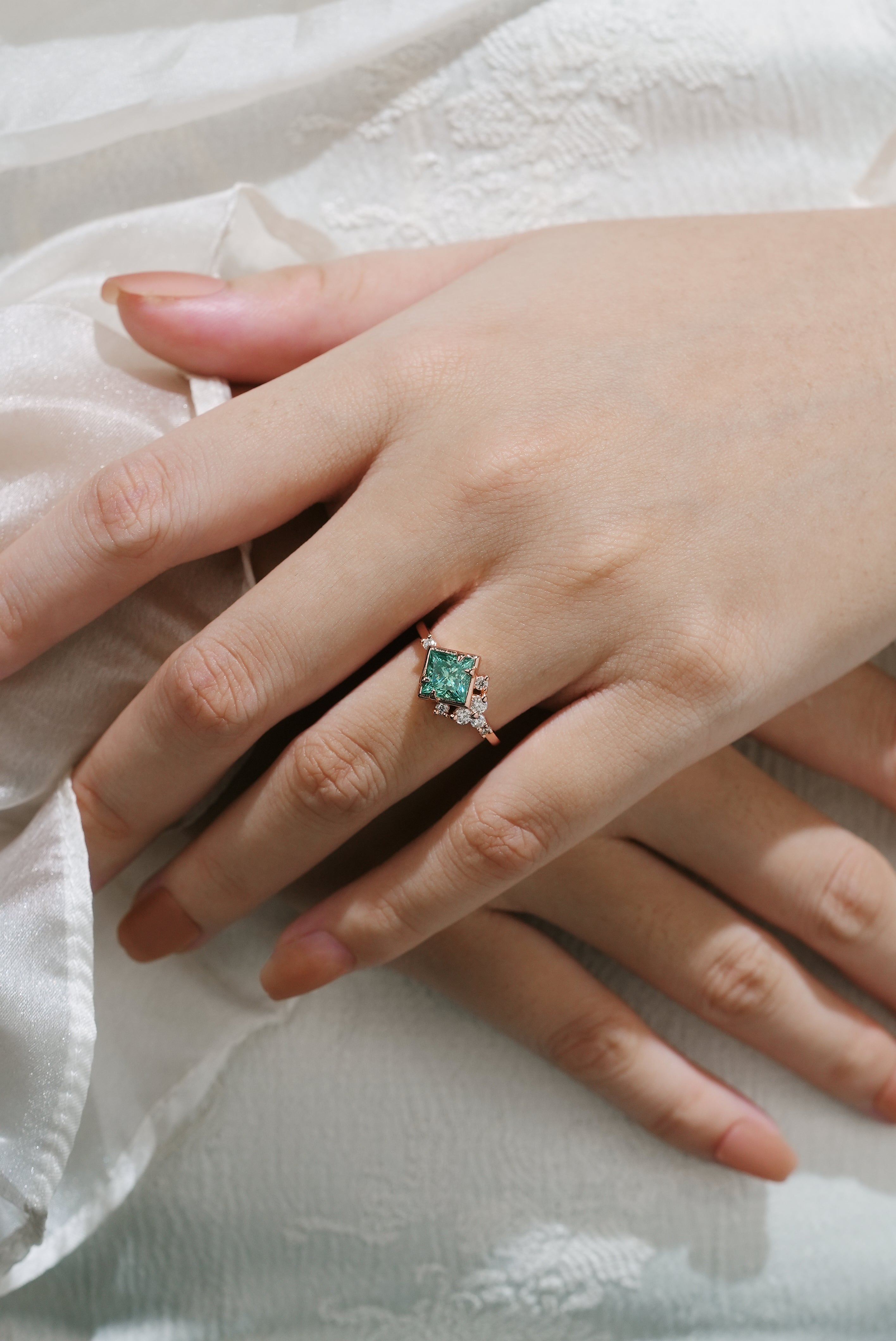 Hand wearing princess-cut green moissanite engagement ring, Lahela Jewelry
