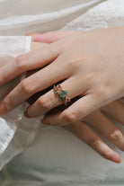 Hand wearing a rose gold moss agate engagement ring with leaf design, accented with moissanite.