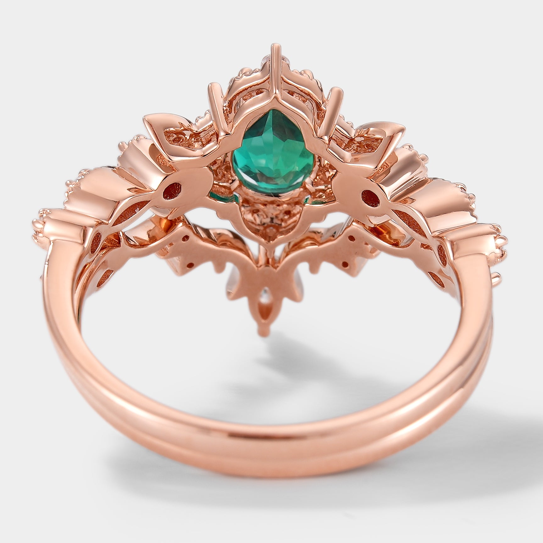 Rose gold emerald and moissanite engagement ring with floral design