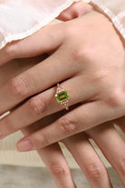 Elegant emerald cut peridot engagement ring in rose gold, adorned with moissanite accents. A vintage style bridal ring.
