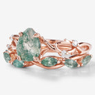 Rose gold moss agate engagement ring set with leaf design, featuring a pear-cut center stone and wedding band.