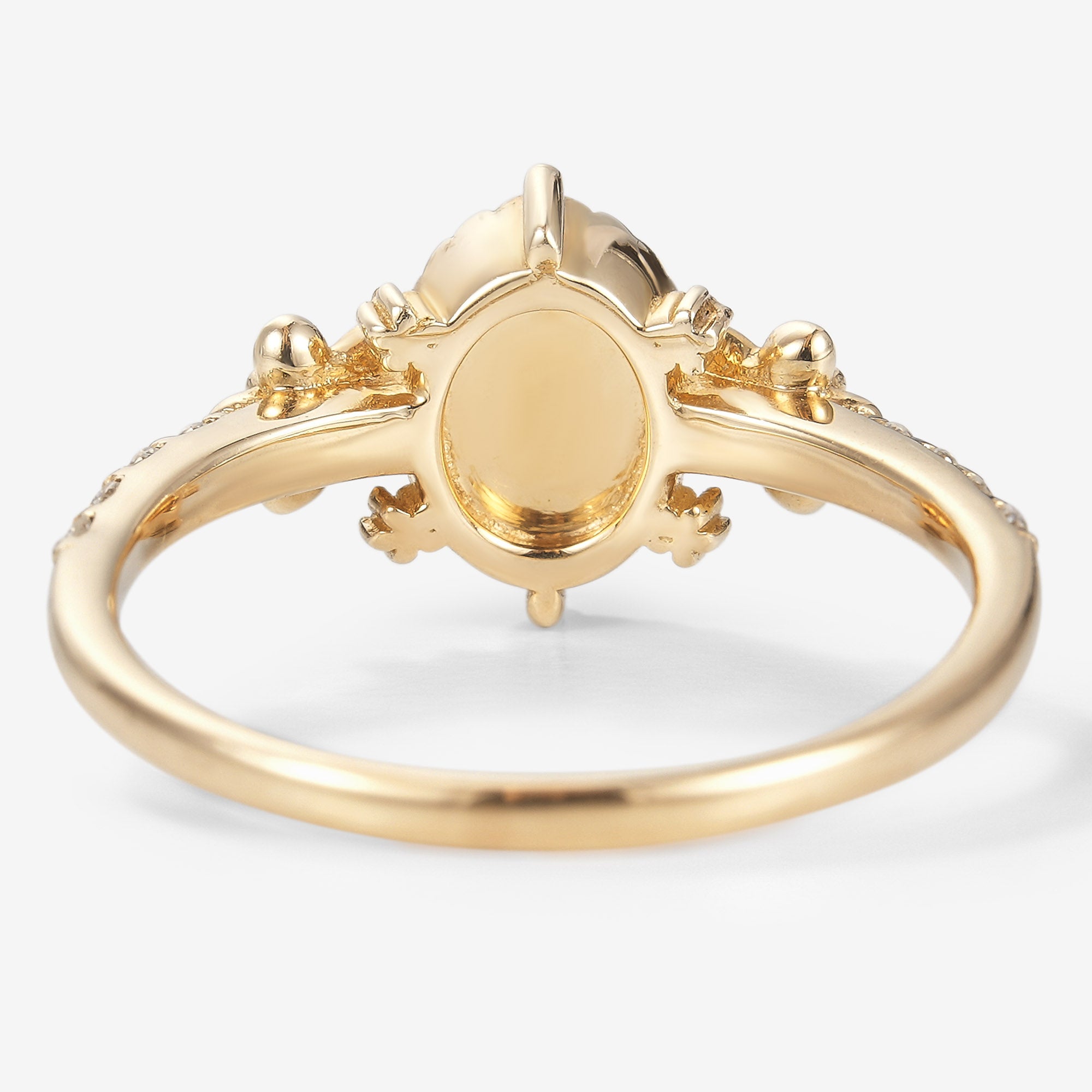 Back view of an oval-cut opal engagement ring in yellow gold, featuring a floral design, bridal set.