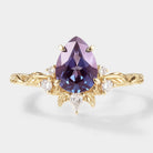 Vintage pear-cut alexandrite engagement ring with gold band and moissanite accents. Leaf design.