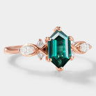 Rose gold engagement ring with a long hexagon-cut lab-grown emerald center stone and moissanite accents, vintage style.