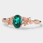 Oval lab grown emerald engagement ring in rose gold with leaf design, moissanite accents, vintage style