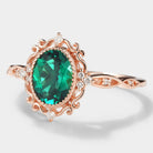 Vintage rose gold emerald engagement ring with moissanite accents. Lab-grown emerald ring with intricate filigree detailing.