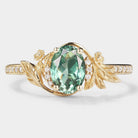 Oval green sapphire engagement ring with leaf and flower accents in gold
