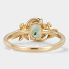 Oval lab grown green sapphire engagement ring with leaf and flower accents in gold