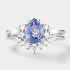 Pear cut cornflower sapphire engagement ring with a curved moissanite wedding band. Bridal set in white gold