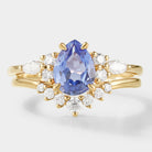 Pear-cut cornflower sapphire engagement ring with curved moissanite wedding band in yellow gold. Bridal set.