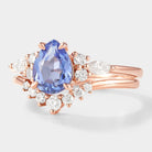 Rose gold pear-cut cornflower sapphire engagement ring with curved moissanite wedding band. Bridal set.